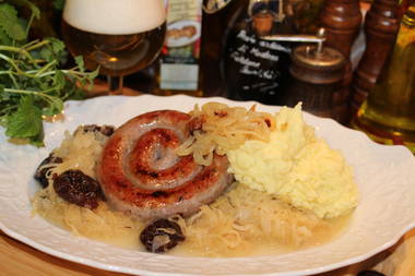 Schneckenbratwurst mit Sauerkraut, Kartoffelbrei und Backpflaumen