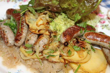 Majoran-Würstle auf Sauerkraut, Zwiebeln und frischen Kartoffelscheiben